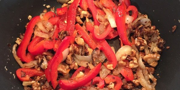 De uien, walnoten en paprika in de hapjespan